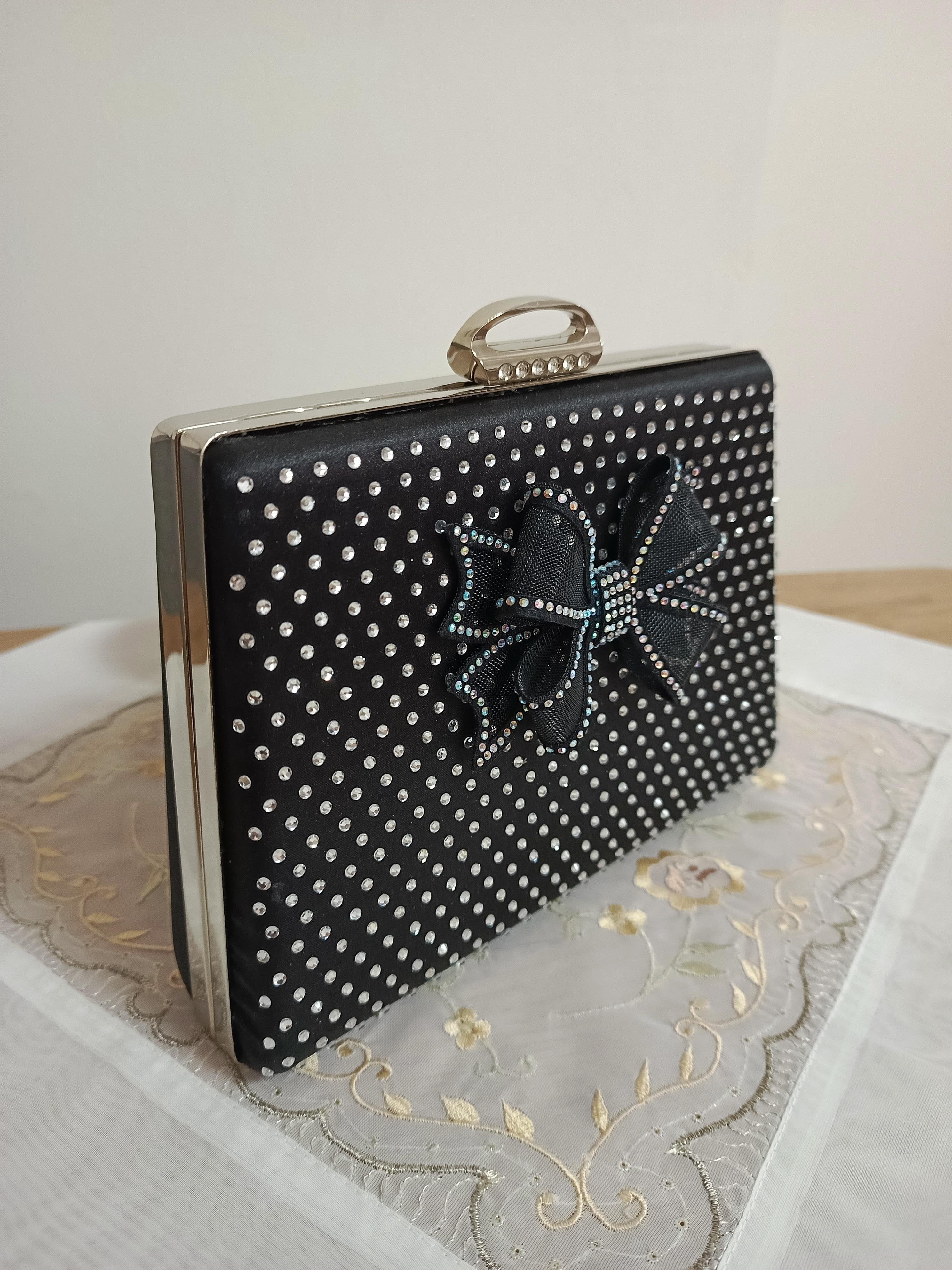 Schwarze Abendclutch mit Schleife und Strasssteinen sowie Kettenriemen