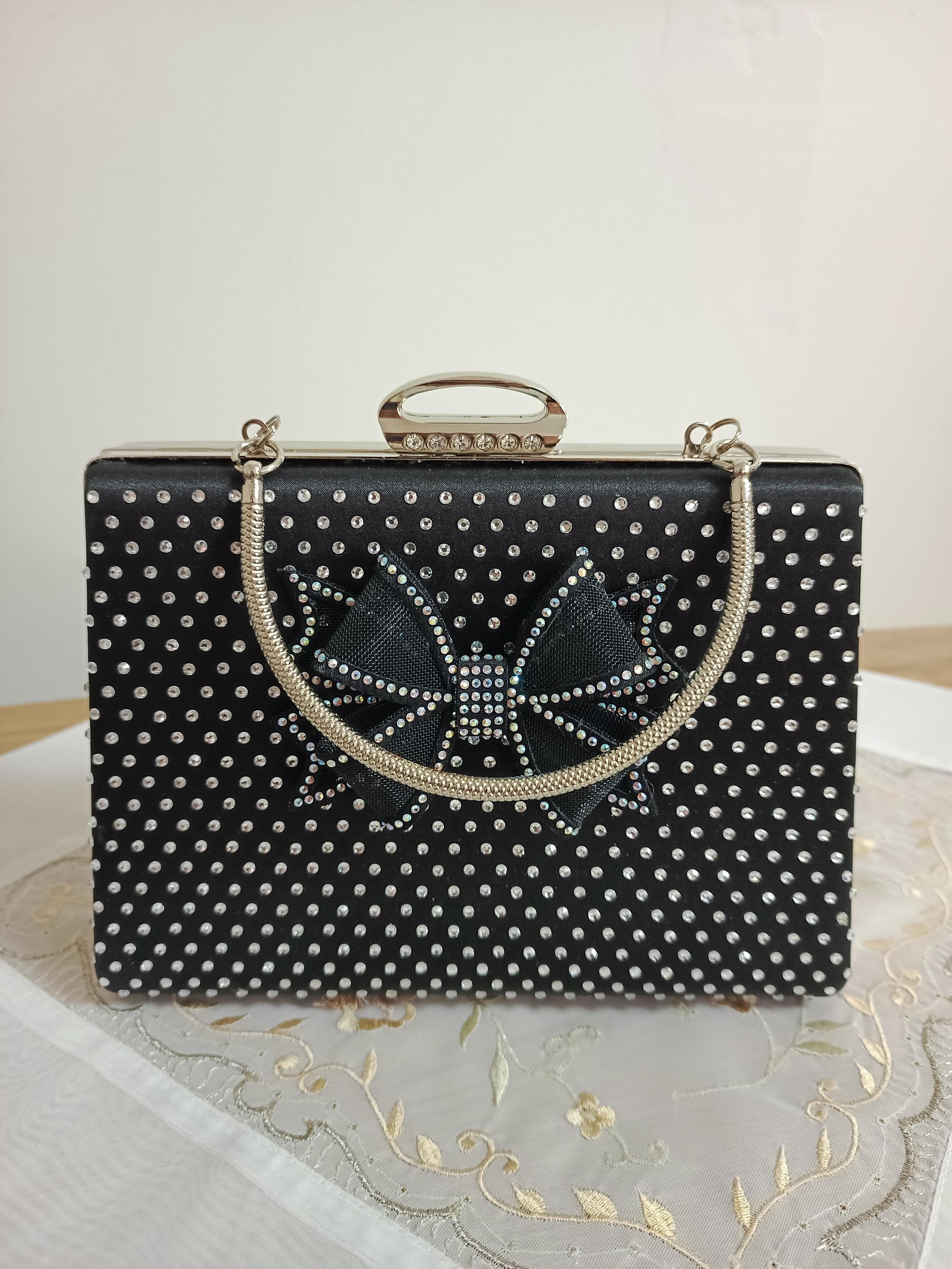 Schwarze Abendclutch mit Schleife und Strasssteinen sowie Kettenriemen